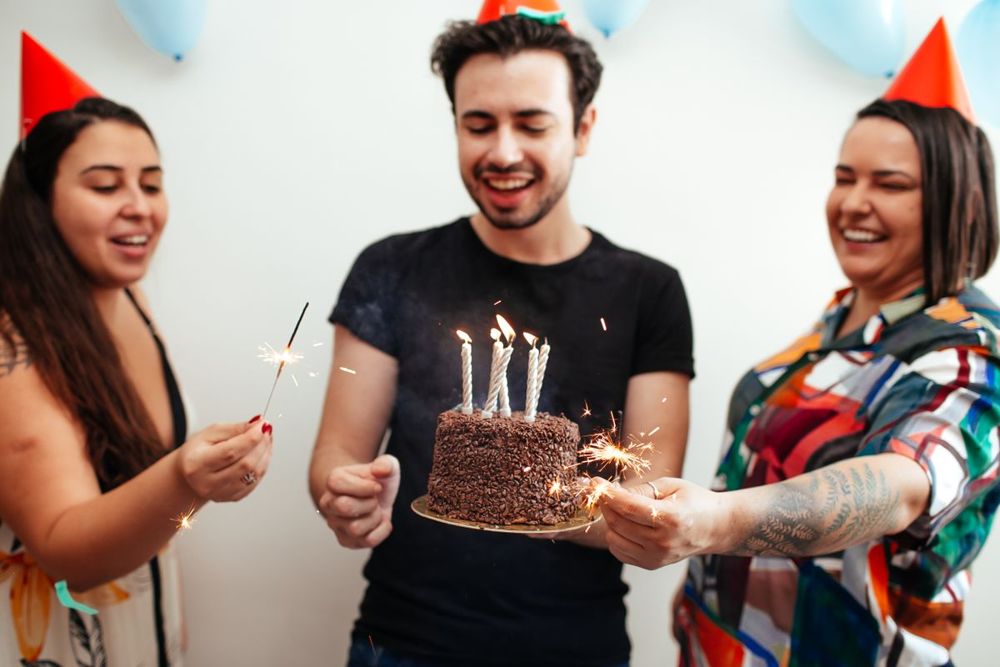 Friends celebrating with a chocolate birthday cake and candles